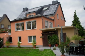 Une maison dotée de panneaux solaires, d’un patio couvert et de plantes en pot.