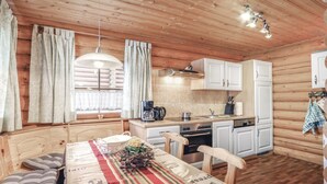 A cozy wooden cabin with a dining area, kitchen, and a large window with curtains. - Cozy home in Harzgerode/Dankerode (Harzgerode/Dankerode)