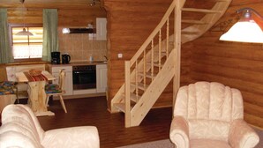 A cozy cabin interior with a wooden staircase, a dining area with a table and chairs, and a kitchen with a stove and sink. - Cozy home in Harzgerode/Dankerode (Harzgerode/Dankerode)
