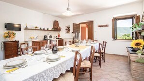 Una zona de menjador amb taula ben a punt per a sis persones, una cuina de fons i una finestra amb vistes.