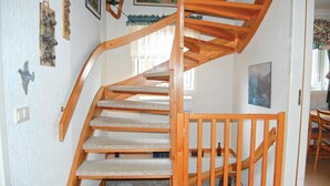 A wooden spiral staircase with a handrail and carpeted steps leading to an upper floor.
