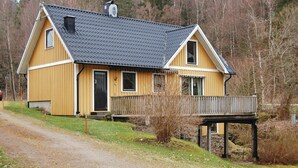 A two-story wooden house with a dark roof, a front porch, and a small deck.