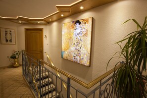 Un escalier avec une rampe, un tableau au mur et une porte.