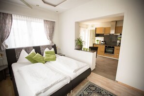 Une chambre d’hôtel moderne avec un grand lit, un petit bureau et une vue sur la cuisine.