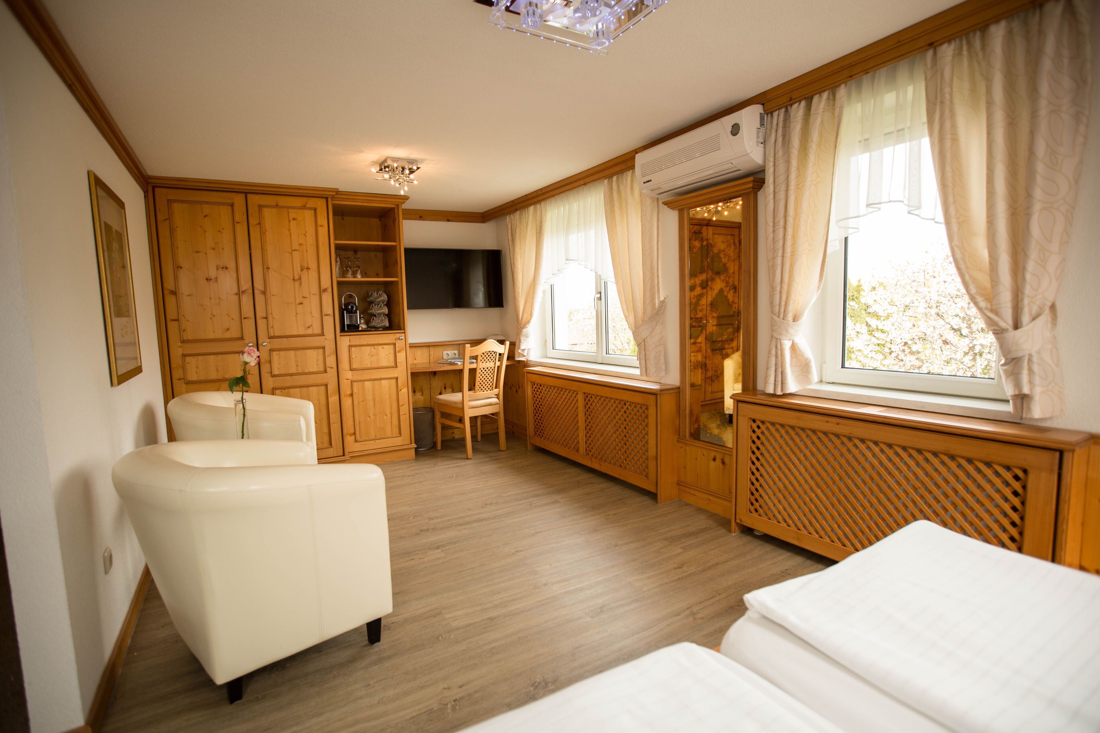 Ein Zimmer mit Sofa, Sessel, Schreibtisch und Bett.