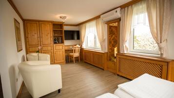 Ein Zimmer mit Sofa, Sessel, Schreibtisch und Bett.