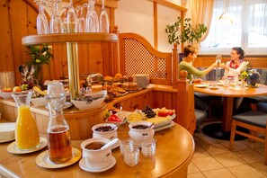 Un buffet de petit-déjeuner proposant une variété d’aliments et de boissons, des meubles en bois et une fenêtre laissant entrer la lumière naturelle.