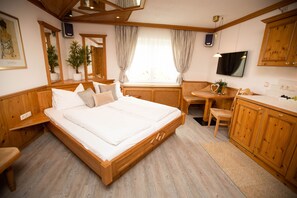 Un dormitorio de madera con cama, mesita de noche, silla, escritorio y armarios.