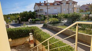 A residential area with a staircase leading to a gated entrance, surrounded by greenery and houses.