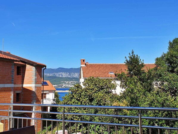A view of a building with a red-tiled roof, surrounded by greenery and overlooking a mountainous landscape.