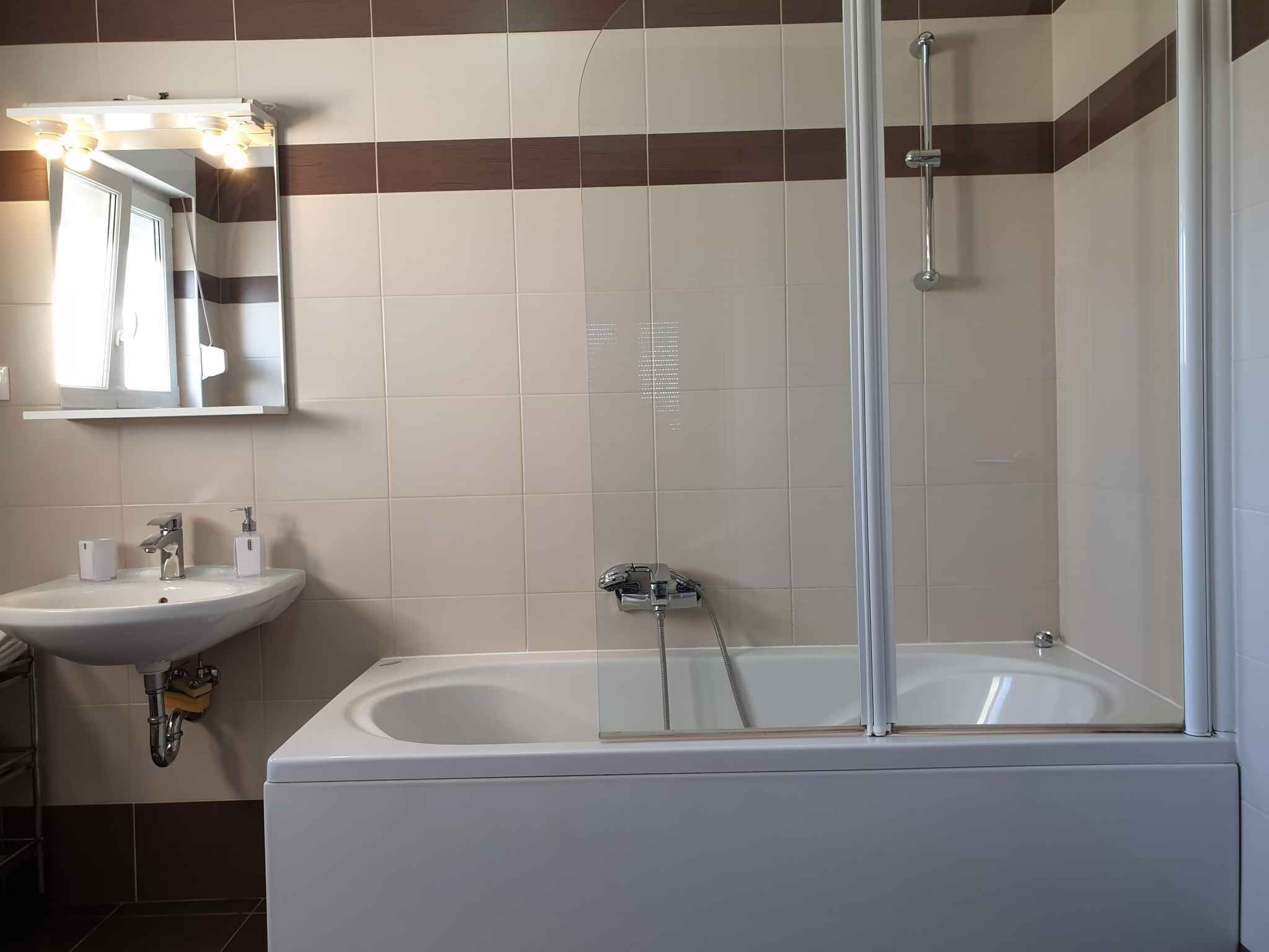 Een moderne badkamer met een bad, douche en wastafel.
