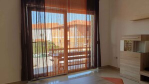 A modern room with a large sliding glass door, a wooden cabinet, and a tiled floor.