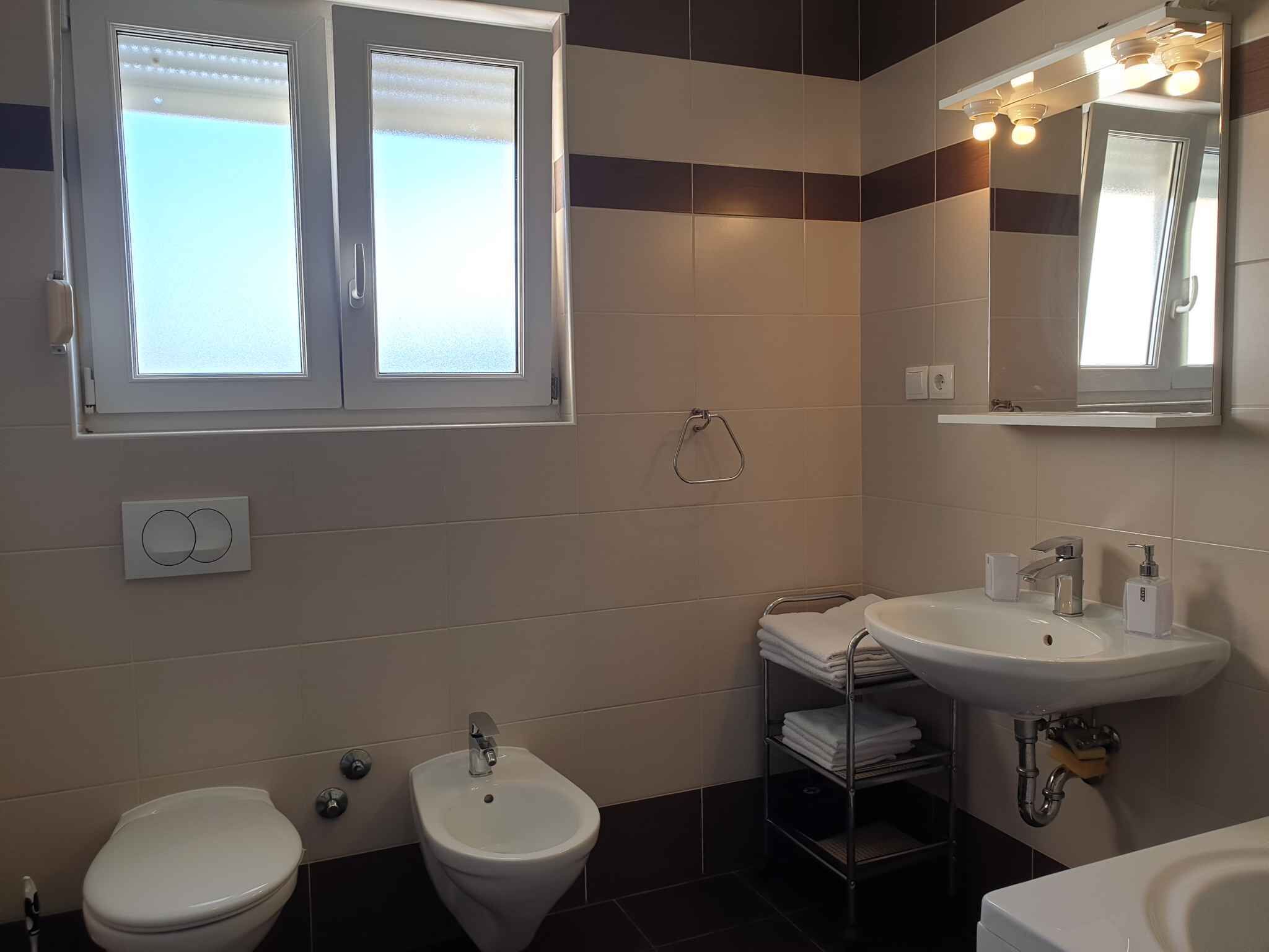 A bathroom with a bidet, a toilet, a sink, and a mirror.