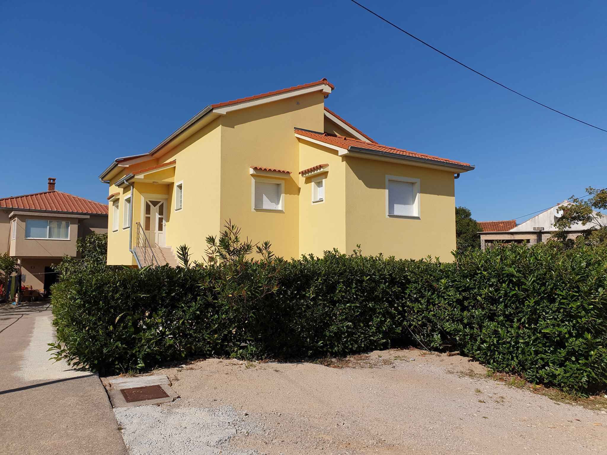 Ein zweistöckiges Haus mit gelber Fassade und rotem Ziegeldach.