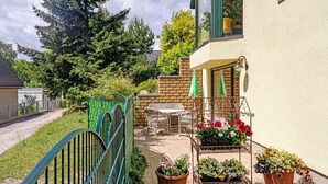 A patio with outdoor furniture, a metal gate, and potted plants.