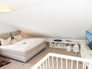 Ein modernes Schlafzimmer mit Bett, Schreibtisch und Fernseher.