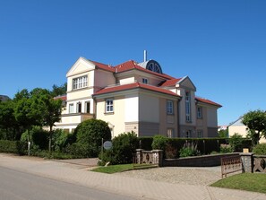A large, two-story building with a red-tiled roof and a prominent dome on the second floor.