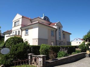 Ein großes, mehrgeschossiges Gebäude mit roter Ziegeldach und einer markanten Kuppel.
