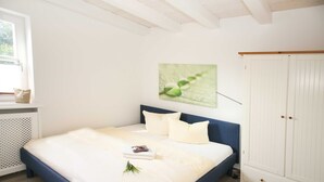 A bedroom with a bed, a white wardrobe, and a window with a view of greenery. - Residence Störtebeker Whg. FB20-18 .. - Residenz Störtebeker Whg. 18 (Kühlungsborn)