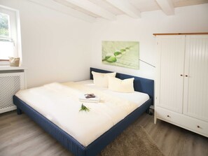 Una camera da letto con un letto, un'armadio bianco e una finestra vista sul verde.