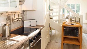 A modern kitchen with a built-in oven, a toaster, and a coffee maker. There is a wooden table with a magazine and a laptop. - Residence Störtebeker Whg. FB20-18 .. - Residenz Störtebeker Whg. 18 (Kühlungsborn)