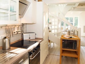 Una cucina moderna con forno integrato, tostapane e macchina del caffè. Si nota un tavolo di legno con una rivista e un computer portatile.