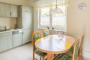 A kitchen with a dining table, chairs, a window with a view, and a clock on the wall. - FH Herve, Monica GM 69206-FH Cather (Graal-Müritz)