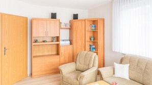 A living room with a sofa, armchair, wooden bookshelves, and a coffee table. - FH Herve, Monica GM 69206-FH Cather (Graal-Müritz)