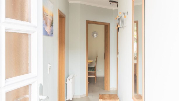 A hallway with a wooden bench, a door, and a mirror on the wall. - FH Herve, Monica GM 69206-FH Cather (Graal-Müritz)