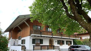 Un chalet traditionnel avec une façade en bois, de nombreux balcons et une voiture garée devant.
