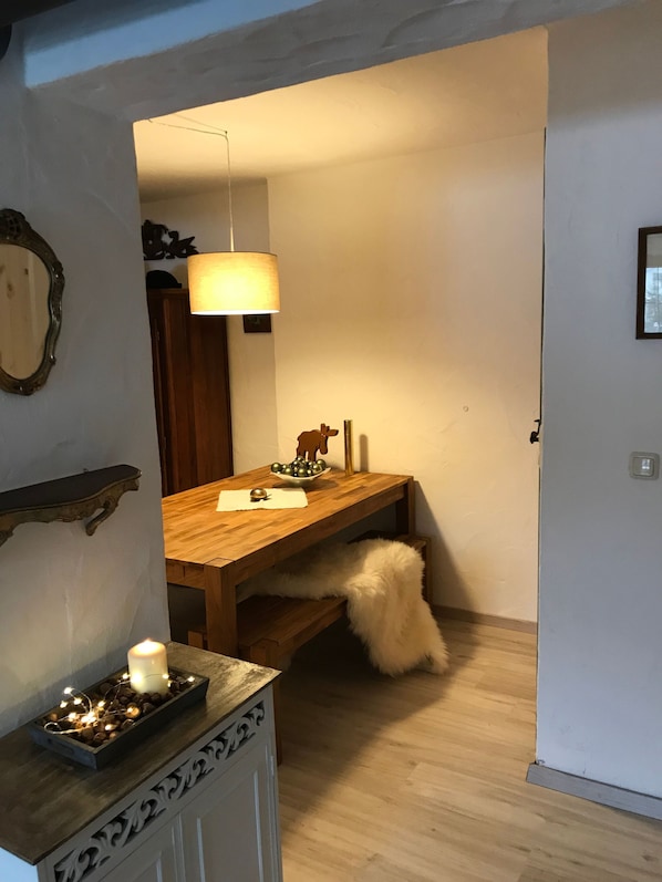 Un coin repas avec une table en bois, une lampe suspendue, une bougie et un bol décoratif.