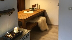 Un coin repas avec une table en bois, une lampe suspendue, une bougie et un bol décoratif.