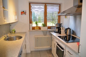 A kitchen with a sink, stove, and window overlooking a garden.