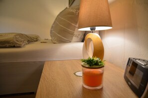 Une table de chevet avec une lampe, une petite plante et une horloge numérique.