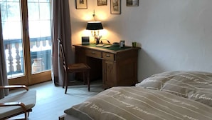 Une chambre à coucher avec un lit, un bureau, une chaise et un balcon.