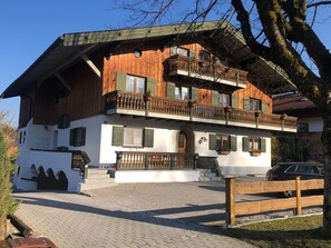 Ein traditionelles Holzhaus mit Balkon, befestigter Auffahrt und Holzzaun.