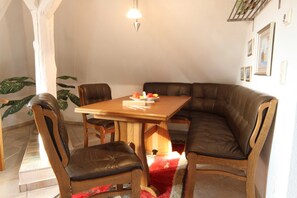 Un comedor con mesa de madera y sillas de cuero, alfombra roja y lámpara colgante.