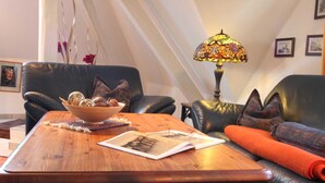Ein gemütliches Wohnzimmer mit einem Holztisch, einer Schale mit Dekoration und einer Lampe mit Buntglasbirke.