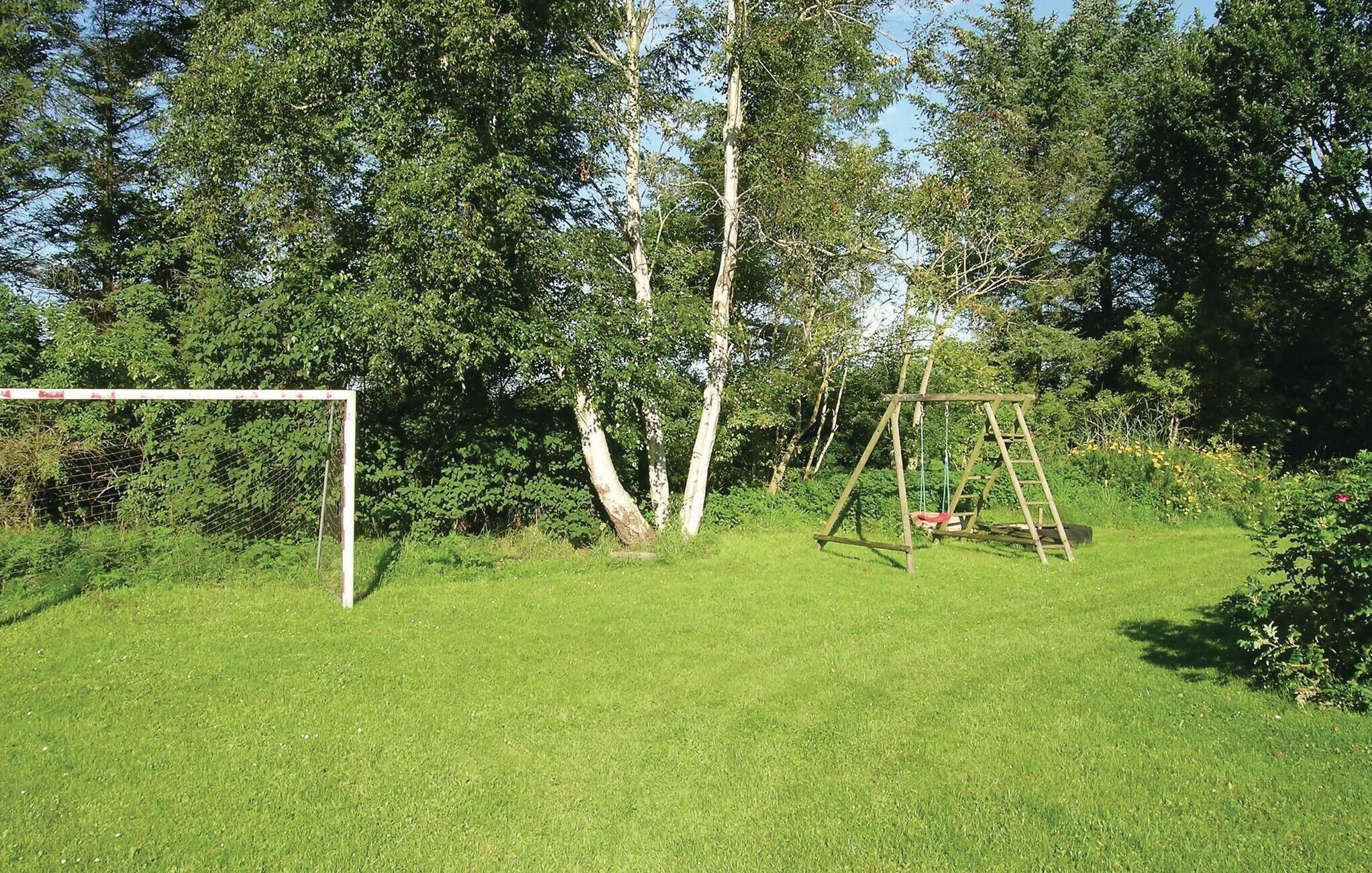 Een gazon met een houten schommel en een voetbaldoel.