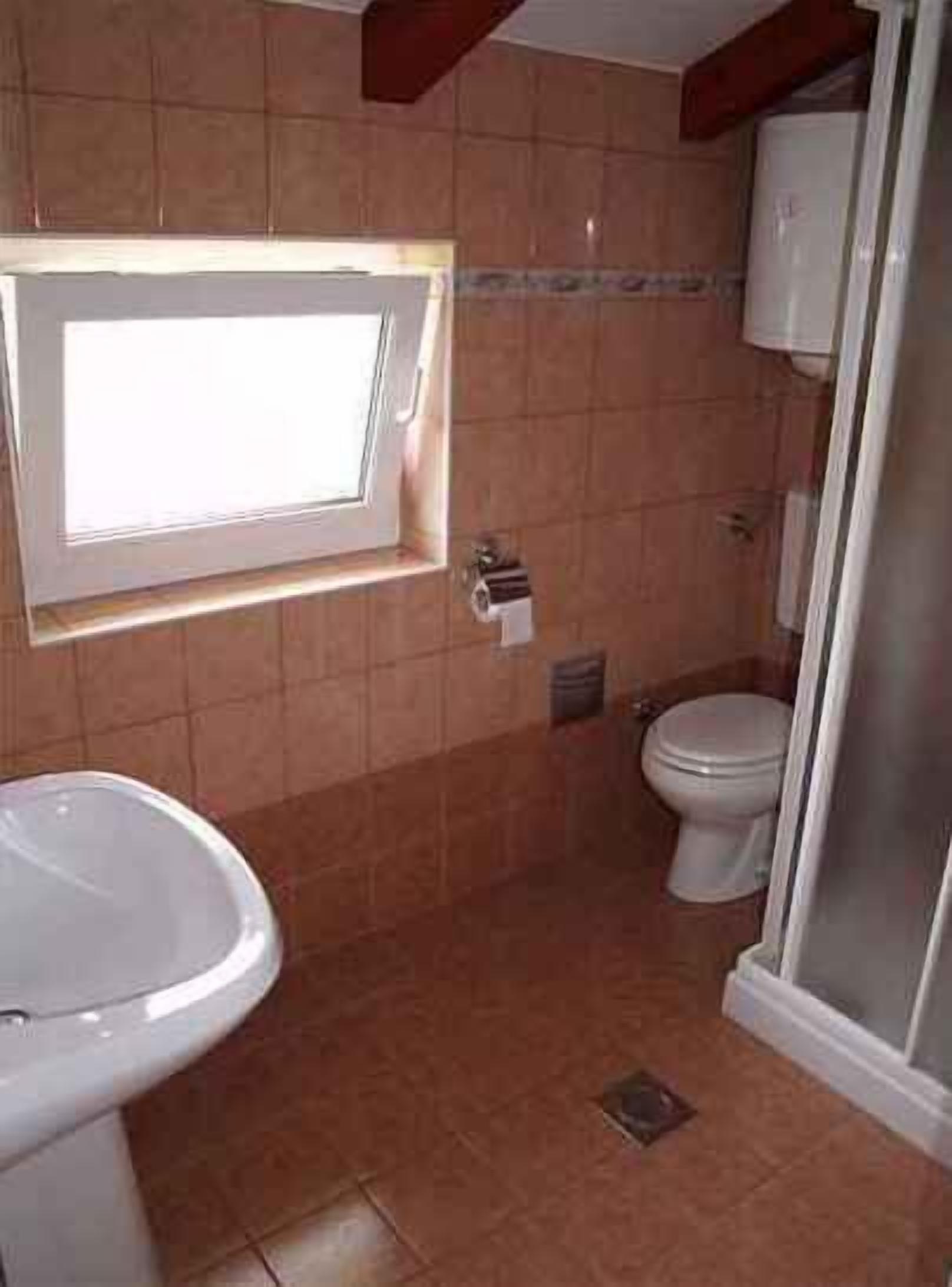 Ein Badezimmer mit Toilette, Bidet und einem Fenster über dem Waschbecken.