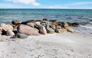 Ein Strand mit großen Felsen und einem Sandufer.
