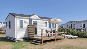 A small, single-story mobile home with a deck and outdoor furniture.