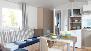 A compact kitchen with a dining area, a window with curtains, and a kitchenette.