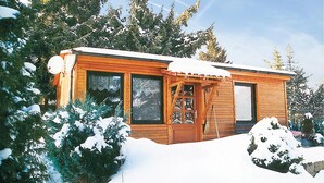 A wooden cabin with large windows, a door with glass panels, and a snow-covered roof. - 2 bedroom amazing home in Thale/Friedrichsbrunn (Thale/Friedrichsbrunn)