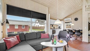 Een moderne woonkamer met een hoekbank, een ronde salontafel en een eetgedeelte met een tafel en stoelen.