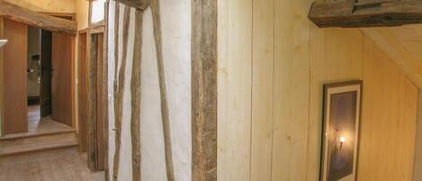 Un couloir avec des poutres en bois apparentes et un tableau encadré accroché au mur.