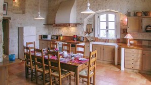Una cocina rústica con muebles de madera, una mesa de comedor preparada para cuatro personas y una pared de piedra.
