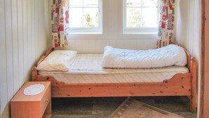 A small, single-bed room with a wooden frame, a wooden nightstand, and a window with curtains. - Amazing home in Jondal with WiFi (Jondal)