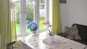 A dining area with a table set for two, a window with curtains, and a view of greenery outside. - Amazing home in Jondal with WiFi (Jondal)