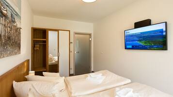 Ein Hotelzimmer mit einem Bett, einem an der Wand montierten Fernseher und einer Tür zu einem Badezimmer.
